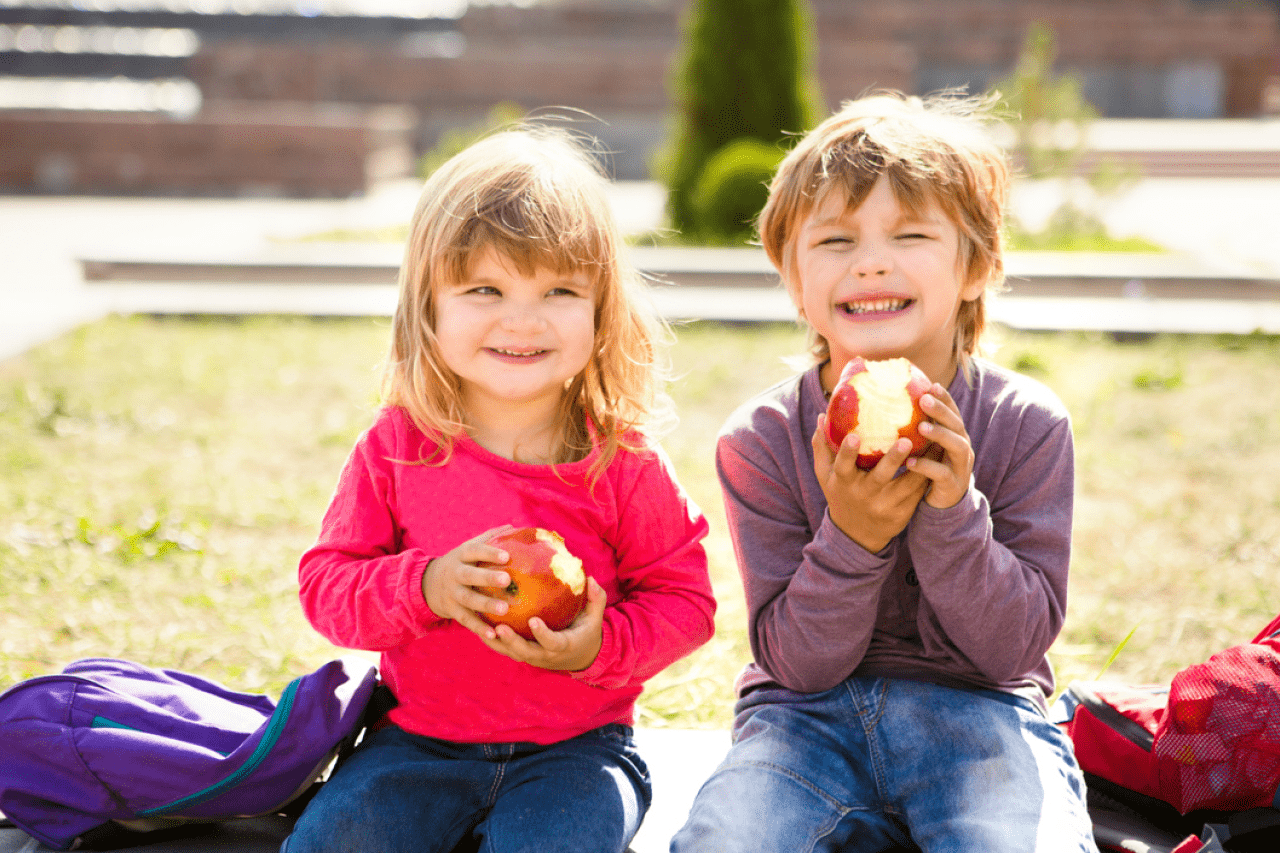 Kinderen die naar school gaan met boekentas gevuld met een gezonde snack.